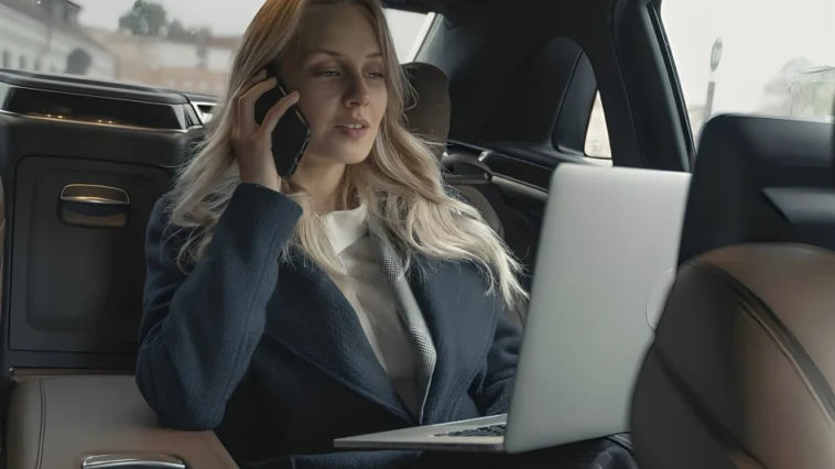 Kobieta podróżująca samochodem na tylnym siedzeniu pracująca przy komputerze